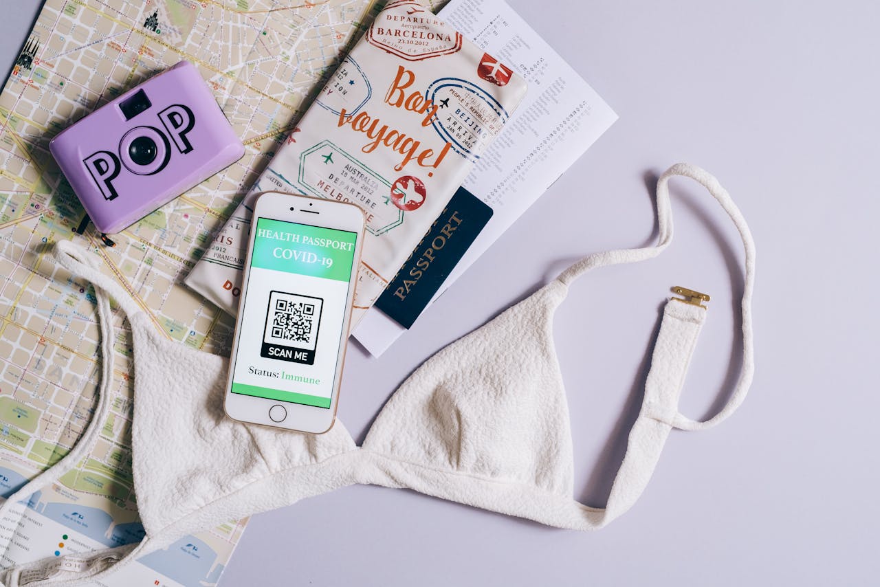 Flat lay of travel items including a COVID health passport, map, and bra, highlighting travel readiness.